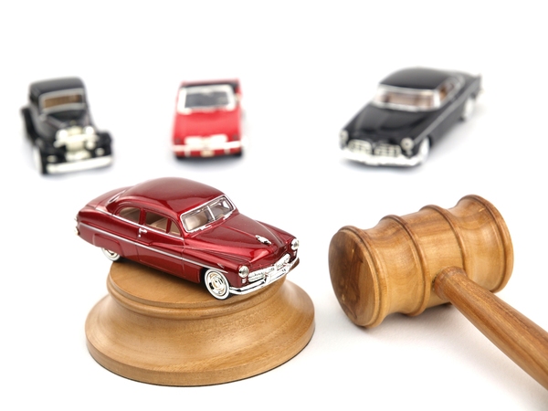Wooden gavel with vintage model cars illustrating auction bidding strategy and how to access dealer auctions for cheap used cars through dealer auction access
