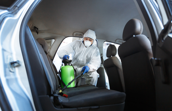 Professional technician disinfecting the interior of the car and addressing biohazard restoration costs for a flooded vehicle and biohazard restoration costs for low-priced auction car buyers