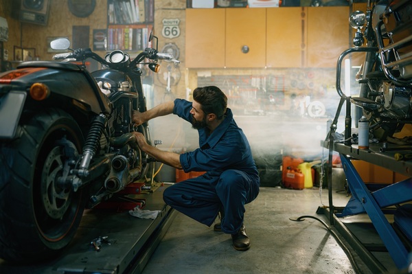 Mechanic inspecting a salvage motorcycle in a workshop performing a VIN check and assessment of the motorcycle and salvage title before buying salvage motorcycles