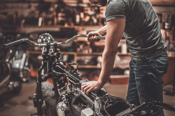Man examining the motorcycle engine during the salvage motorcycle inspection checking flood-damaged motorcycles and theft-recovered motorcycles before purchase