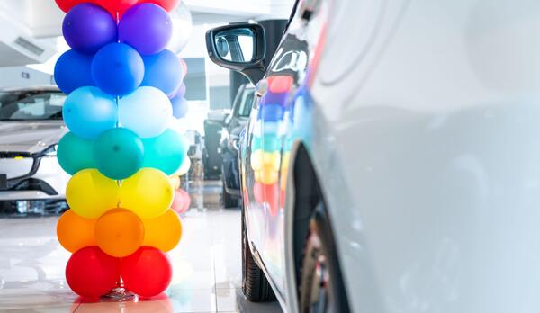 Colorful balloons decorating a car dealership showroom representing holiday car sales and the best time to negotiate a car price