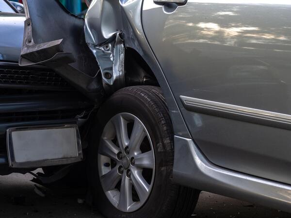 Close-up of a crushed rear panel and bumper on a gray car showing the type of collision damage that results in a salvage title car being declared a total loss vehicle