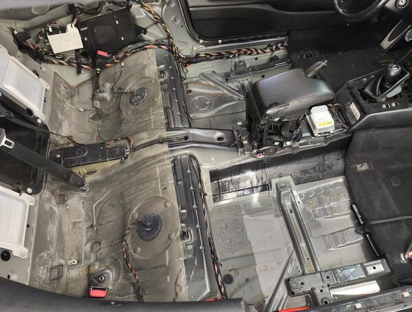 Fully stripped car interior exposing bare metal floor and wiring harnesses representing the repair process involved in how to rebuild a salvage title and restore a rebuilt title car