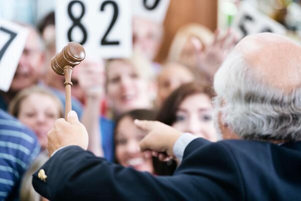 Auctioneer with gavel facing bidders at a live Los Angeles car auction perfect for car auction tips for beginners